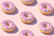 Pink doughnuts pattern on a pink background. Trendy summer aesthetic backround. Vibrant colors with sparkle and glitters. Sweet food donut visual concept.