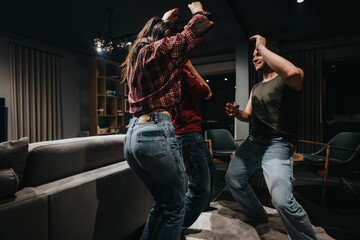 Wall Mural - A group of friends enjoying a lively dance in the comfort of a warm, well-decorated living room during a relaxed social gathering.