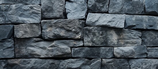 Wall Mural - A closeup of a grey brick wall made of composite materials. The pattern of rectangular black bricks resembles cobblestone, creating a solid bedrocklike structure