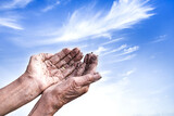 Fototapeta  - Soiled hands of elderly women with soft blue sky, hope full in new better life