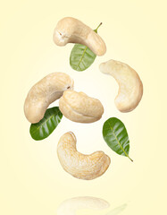 Canvas Print - Cashew nuts with green leaves flying in the air isolated on yellow background.