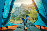 Fototapeta  - A woman stretching her feet with shoes on, against a natural backdrop. A tourist woman resting in a camping tent