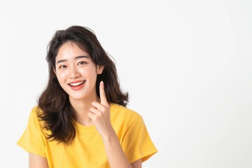 Wall Mural - Young Asian woman in yellow shirt pointing to empty space.