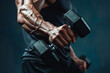An attractive athletic man’s arm with dumbbells