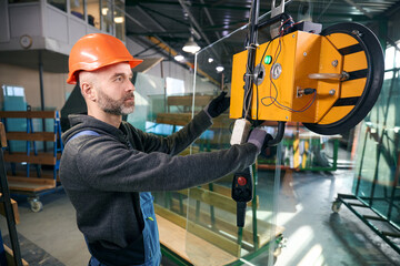 Worker uses a vacuum lifting device in a window production