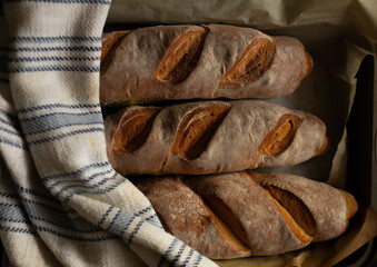 Wall Mural - Three baguettes on baking pan with cotton towel. Sliced bread texture