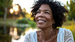 © Keitma - Black american woman in her 50s who exudes happiness and a sense of feeling truly alive in a beautiful natural park near a lake, genuine smile on her face, relaxed and confident, female who found joy