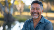 © Keitma - Latino american man in his 50s who exudes happiness and a sense of feeling truly alive in a beautiful natural park near lake, genuine smile on his face, relaxed and confident latin male who found joy