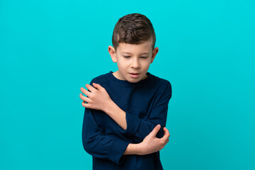 Wall Mural - Little kid boy isolated on blue background with pain in elbow