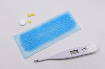 medical digital thermometer, cooling fever patch gel and medicinal pills on white background. basic 