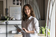 © fizkes - Happy attractive young manager woman holding tablet, using online application for business tasks, touching screen, looking at camera for portrait, enjoying work on successful project