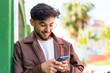 © luismolinero - Handsome Arab man at outdoors sending a message with the mobile