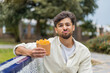 © luismolinero - Young Arabian handsome man holding fried chips at outdoors with sad expression