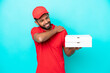 Pizza delivery Brazilian man with work uniform picking up pizza boxes isolated on blue background suffering from pain in shoulder for having made an effort