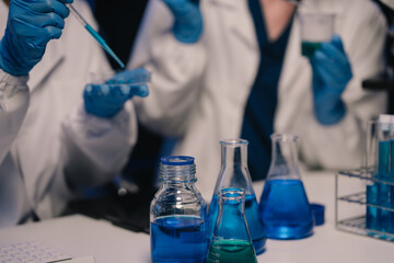 Team of biochemical research scientists working with a microscope for vaccine development in pharmaceutical research labeling.