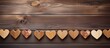 Wooden hearts in a rustic style are arranged on a string, displayed against a textured wooden background