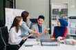© laddawan - Happy businesspeople while collaborating on a new project in an office. Group of diverse businesspeople using a laptop and tablet