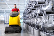 Professional cleaner operating industrial floor cleaning machine inside the factory.