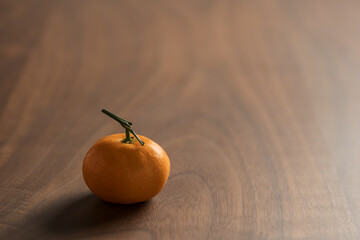 Wall Mural - Small organic tangerine with stem on wood table