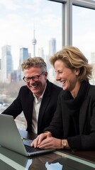 Wall Mural - Blond man and woman in dark suit looking at laptop and laughing