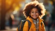 Portrait of a happy smiling school girl with afro hair wearing a yellow jacket and a backpack