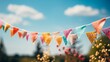Colorful paper flags hanging from a string with a blurred background of a field of flowers and blue sky