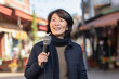 Middle aged Chinese woman at outdoors as a reporter holding a microphone and reporting news