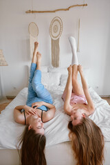 Two young beautiful girl friends on bed enjoying free time together