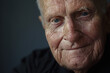 Close-up portrait of an 80-year-old senior man, emanating positivity and vitality with his joyful smile and expressive eyes, against a sleek gray studio backdrop