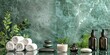 Beauty treatment items for spa procedures on emerald marble table and silver marble wall. massage stones, essential oils and sea salt. candle, rolled up white towel, beautiful plants, copy space