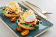 Eggs Benedict with salad leafs, salmon and fresh cherry tomato