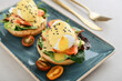 Eggs Benedict with salad leafs, salmon and fresh cherry tomato