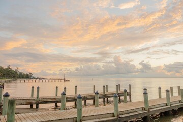 Wall Mural - Closeup of a wooden dock stretching over a body of tranquil water at sunset in Fairhope