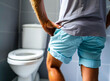 An image depicting a middle-aged man experiencing the discomfort of cystitis, symbolized by his grimace and the gesture of holding his crotch, indicative of painful or difficult urination