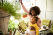 © Marko Geber - Young mother and daughter watering plants and flowers on the balcony of their apartment