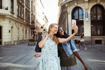 Wall Mural - Two women taking a selfie together on a sunny city street