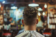 A man sits in a barber shop getting his hair cut