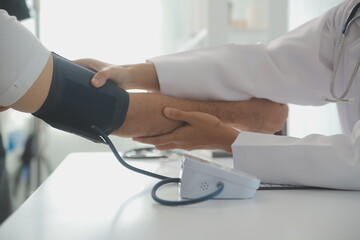 Wall Mural - Male doctor uses a blood pressure monitor to check the body pressure and pulse of the patients who come to the hospital for check-ups, Medical treatment and health care concept.