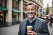 Smiling mature businessman with takeaway coffee on the go
