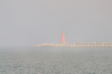 Wall Mural - The Port of Gdansk in the fog, a lighthouse in the foreground. Baltic Sea, Gdansk, Poland