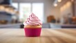 Close up of a fuchsia Cupcake on a wooden Table. Blurred Kitchen Interior Background
