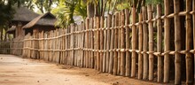 A Picket Fence Made Of Wood Lines The Side Of A Dirt Road, Adding To The Landscape Of The Area With Its Natural And Rustic Design