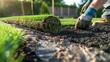 Closeup of a man laying new material for a lawn installation, with green grass rolls and black soil covering the ground