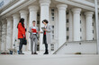 © qunica.com - Three business professionals engaged in a serious discussion with a tablet and papers outside a courthouse.