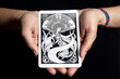 Tarot card in the hands of a woman on a black background. Fortune telling and spiritism concept