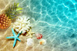 Yellow pineapple, seashells and starfish on a blue water background.
