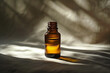A brown bottle of aromatherapy essential oil on a table with sunlight and shadows