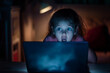 Scared child looking at a laptop screen. Internet safety concept.