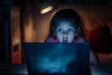 Fototapeta Dmuchawce - Scared child looking at a laptop screen. Internet safety concept.