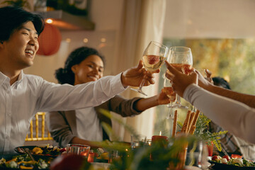 Wall Mural - Close up of happy friends is drinking cocktails and clinking glasses during Christmas party at home